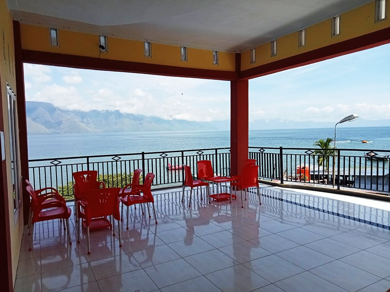 Teras lounge Dermaga Hotel Parbaba menghadap Danau Toba dan perbukitan Samosir